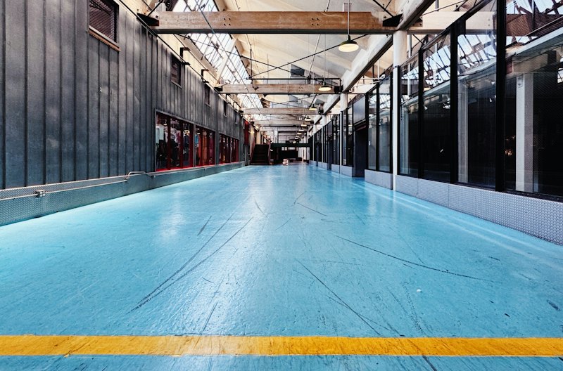 Large room with a blue coated floor and a yellow safety line